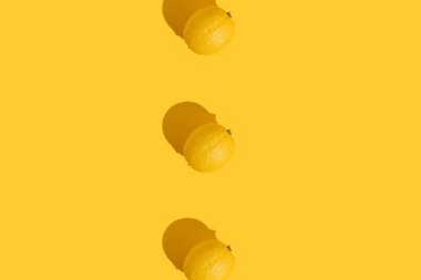 Sarı arka planda sert gölgeli üç limon. Yaz, meyve, vitamin konsepti.
