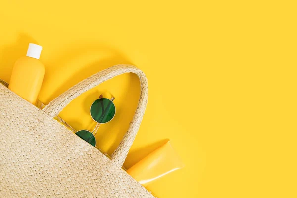 Summer yellow bright flatlay on colorful background with wicker straw bag, tubes and bottle with sunscreen, green sunglasses. Hard shadows and light. Top view. Flat lay. Trend style. Copyspace. — Stock Photo, Image