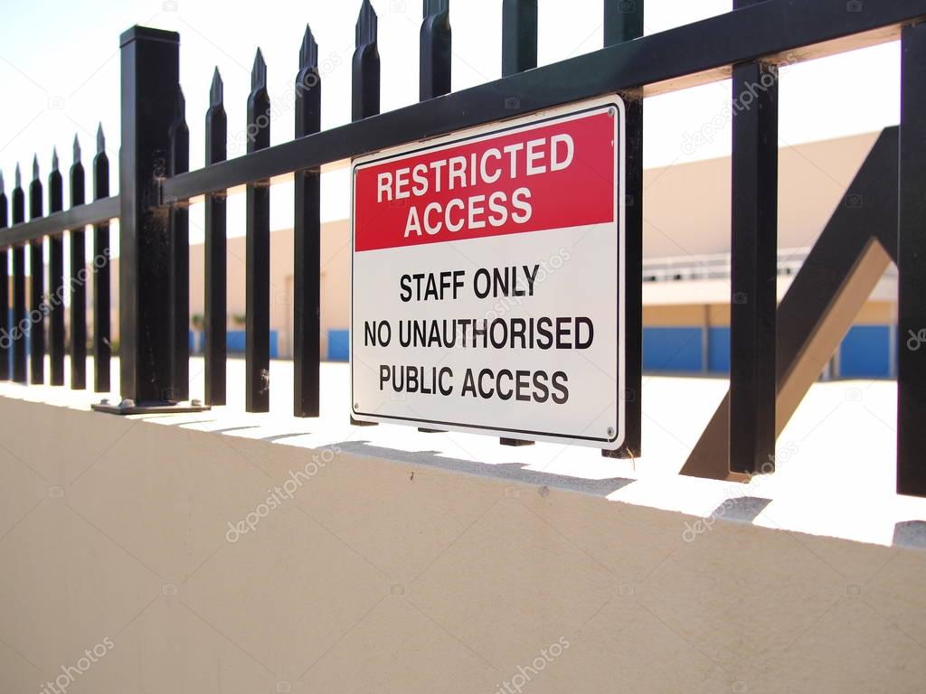 Access restricted sign on a steel fence tipped wall of an industrial estate