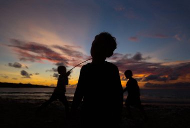 Çocuk oynamak ve eğlenmek gün batımında deniz.