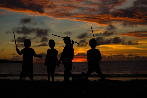 Τα παιδιά παίζουν και να διασκεδάσουν στο ηλιοβασίλεμα δίπλα στη θάλασσα. — Φωτογραφία Αρχείου