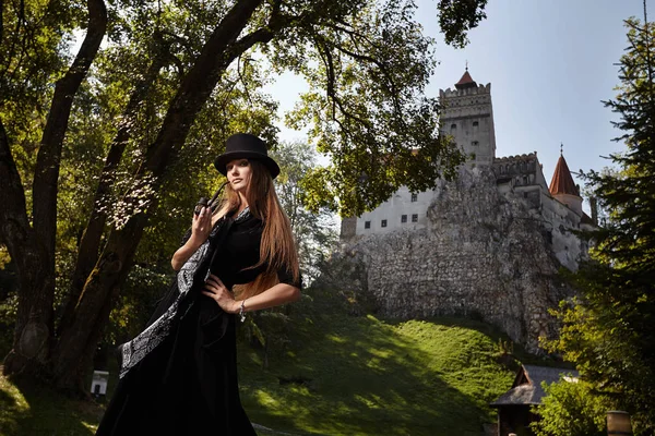 Modelmädchen mit Hut und schwarzem Kleid geht in den Hof des — Stockfoto