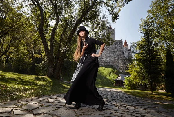 İnci avluda bir şapka ve siyah elbise modeli kız yürüyor — Stok fotoğraf