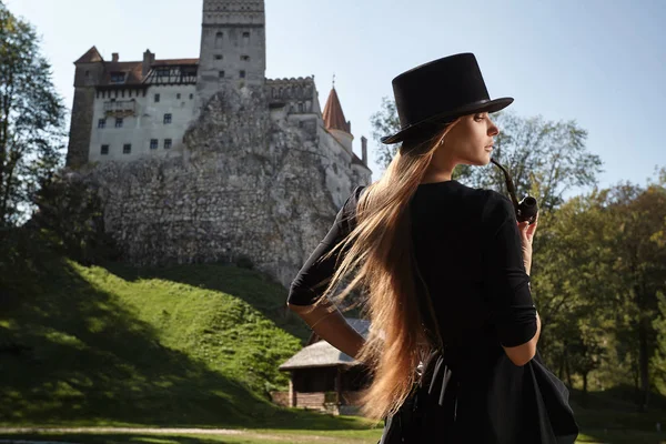 Model meisje in een hoed en een zwarte jurk wandelingen in de binnenplaats van th — Stockfoto