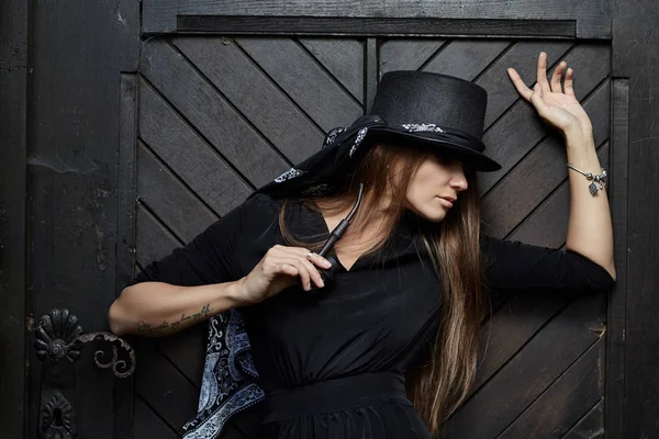Lány modell egy tégla, régi fal egy fekete kalap. — Stock Fotó