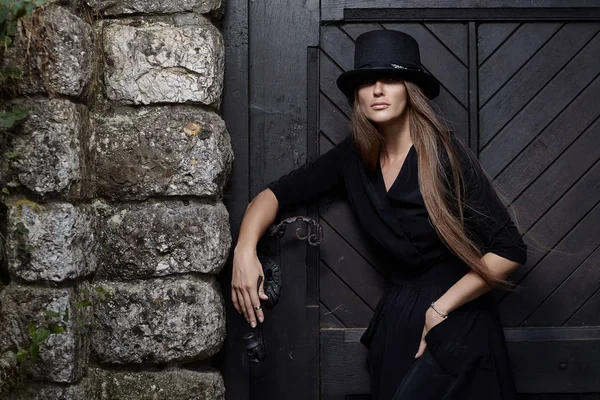 Porträt eines Modelmädchens in schwarzem Kleid und Hut. — Stockfoto