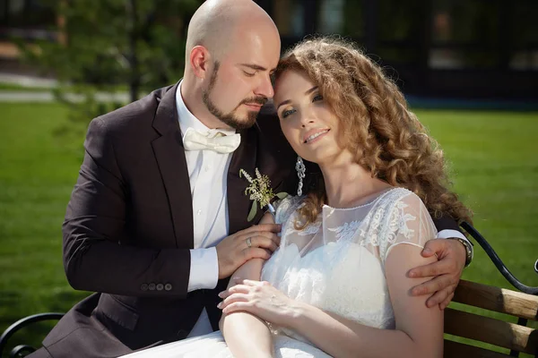 La novia y el novio en el jardín en el banco . — Foto de Stock