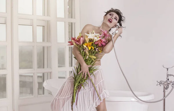 Een meisje met een mooi boeket bloemen in de badkamer. — Stockfoto