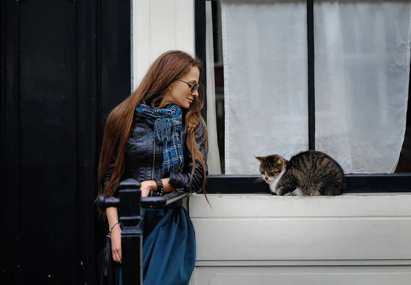 Portrait of a girl, model with a cat on the porch near the house