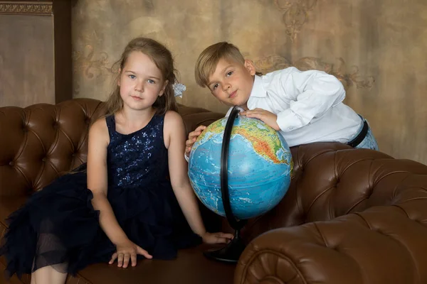 Um menino e uma menina na sala de aula, na escola, olhem para o globo . — Fotografia de Stock