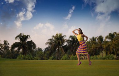 Güzel, zarif bir kız, modeli tropikal bir parkta elini kolunu sallaya dönüyor. Can