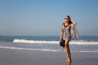 Güzel, zarif bir kız, modeli deniz kıyısı elini kolunu sallaya dönüyor. Can