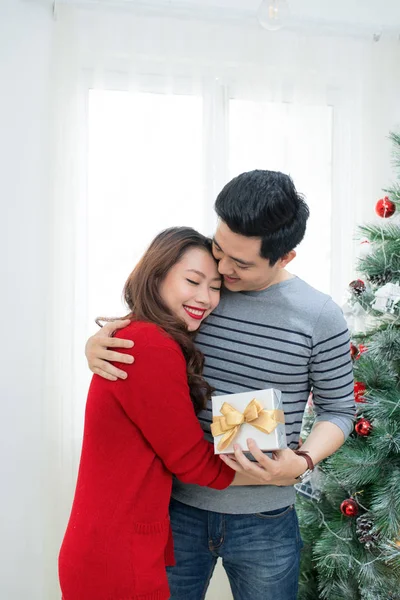 Χριστούγεννα Ασιατισα Ζευγάρι. Ένας όμορφος άνδρας δίνοντας τη φίλη/γυναίκα ένα δώρο στο σπίτι γιορτάζει το νέο έτος άνθρωποι — Φωτογραφία Αρχείου