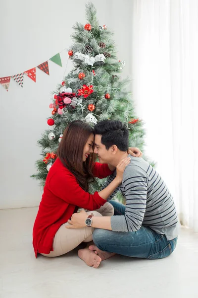 Ζευγάρι συνεδρίαση κοντά στο χριστουγεννιάτικο δέντρο — Φωτογραφία Αρχείου
