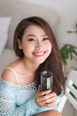 Gülümseyen genç Asyalı kadın yeşil taze sebze suyu o içme