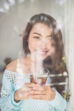 Üzerinde sabah çayını içmeye genç bir Asyalı kadın portresi bir 