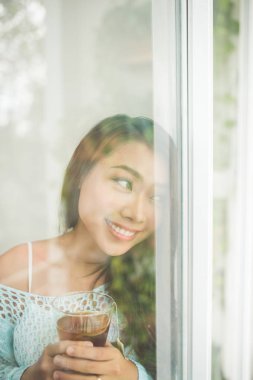 Üzerinde sabah çayını içmeye genç bir Asyalı kadın portresi bir 