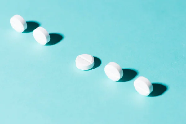 Φάρμακο χάπια σε μια σειρά σε μπλε φόντο. — Φωτογραφία Αρχείου