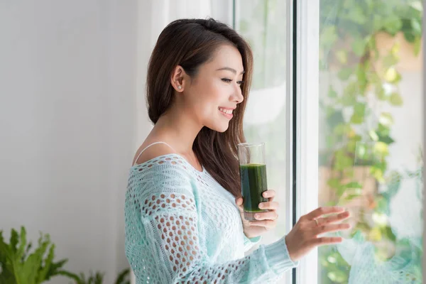 Sonriente joven asiático mujer bebiendo verde fresco vegetal jugo o — Foto de Stock