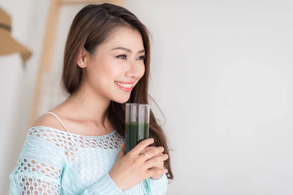 Sorridente giovane donna asiatica bere verde fresco succo di verdura o — Foto Stock