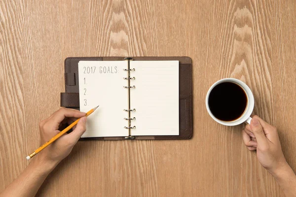 2017 doelen. Bovenaanzicht van hand schrijven op een blanco notebook met warme koffie. — Stockfoto