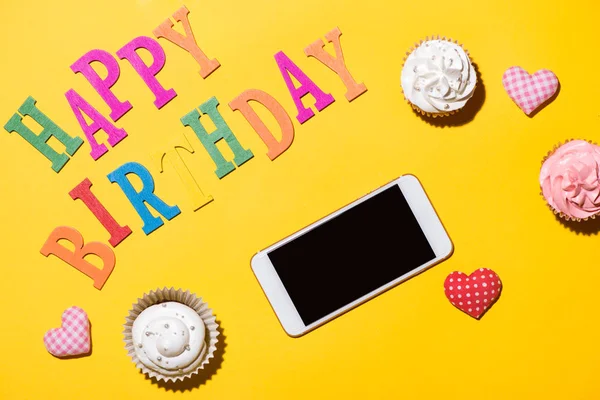 Happy Birthday woorden met cupcakes en smartphone — Stockfoto