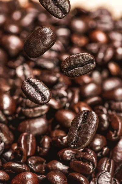 Granos de café oscuro cayendo sobre la mesa — Foto de Stock