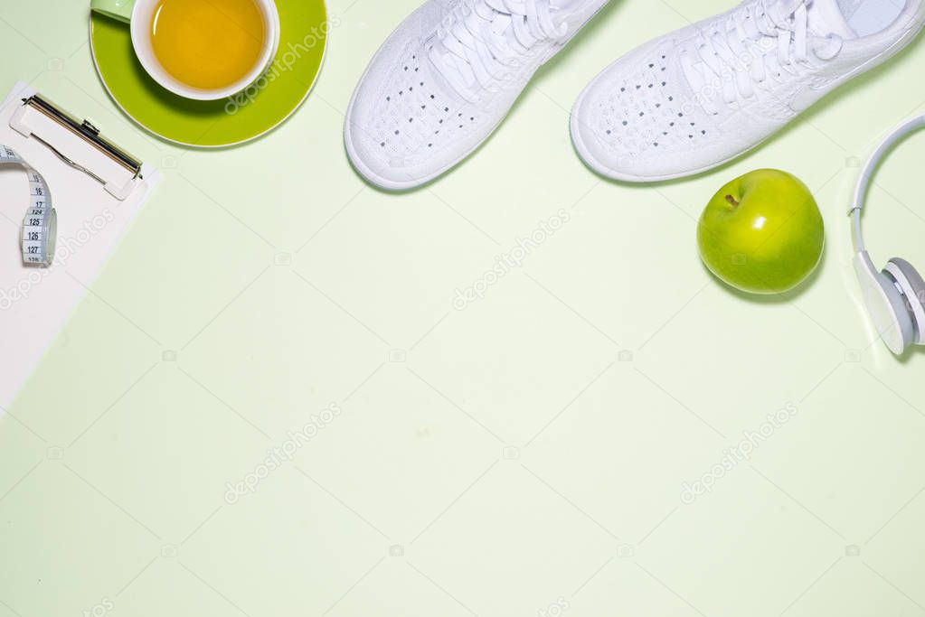 Fitness plan concept. Sneakers, tea, apple and headphone on past