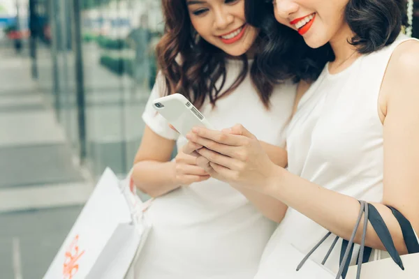 Chicas con bolsas de compras usando smartphone — Foto de Stock