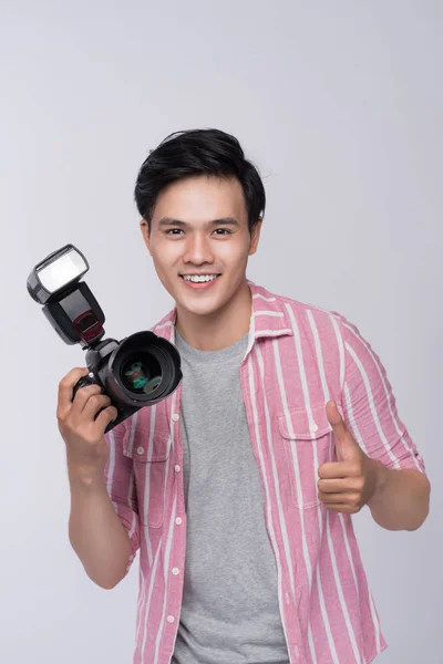 Jovem fotógrafo asiático segurando câmera digital, enquanto trabalhava em estúdio — Fotografia de Stock
