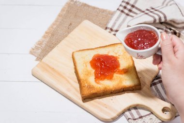 Asyalı kadın kahvaltı için çilek reçelli ekmek yeme. Eller üzerinde odaklanmak