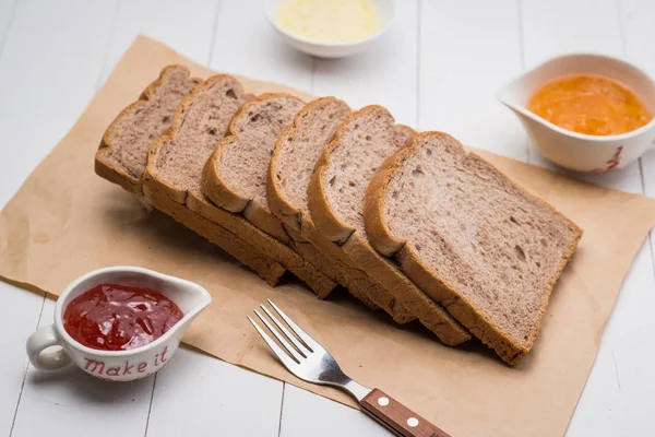 Close-up van sneetje toast brood met jam en boter op houten tafel — Stockfoto