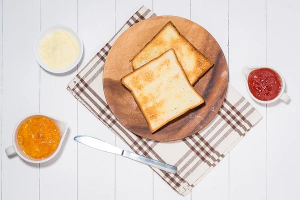 Close-up de fatia de pão torrado com geléia e manteiga na mesa de madeira — Fotografia de Stock