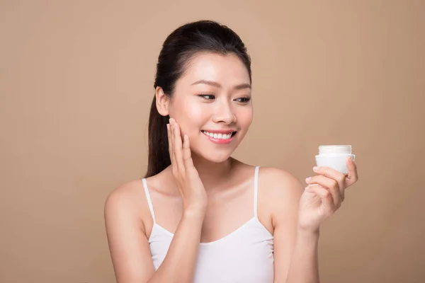 Young woman using moisturizer — Stock Photo, Image