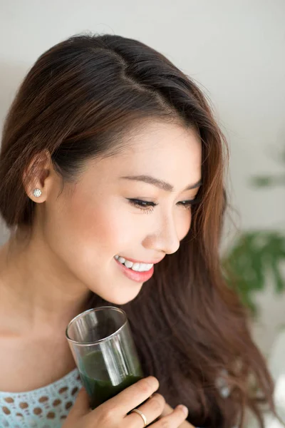 Sorridente giovane donna asiatica bere verde fresco succo di verdura o — Foto Stock