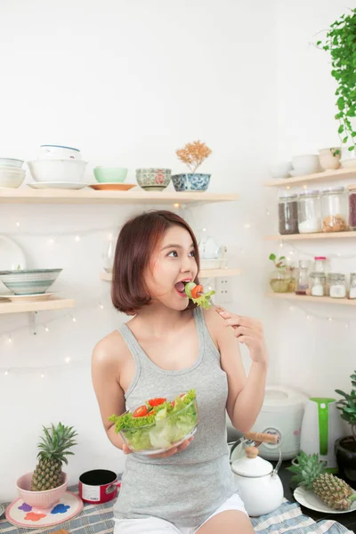 A lány mosolyogva eszik saláta — Stock Fotó