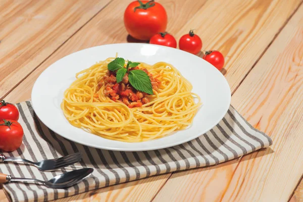 Тарелка вкусных спагетти с томатным соусом и мясом на деревянном столе — стоковое фото