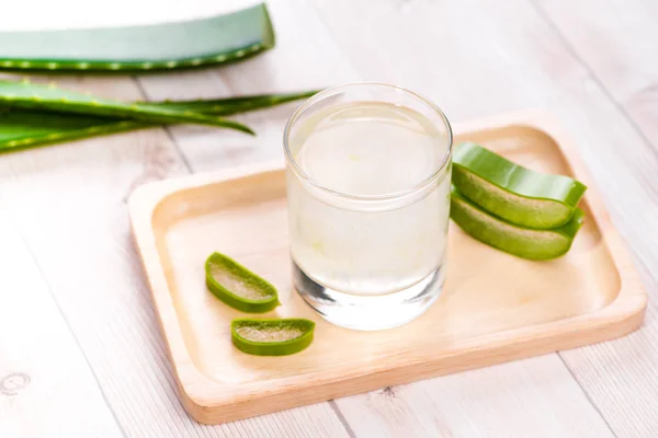 Aloe vera suyu ahşap bir masa üzerinde taze yaprakları ile