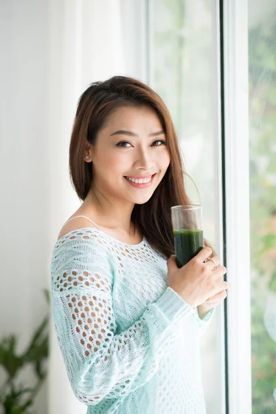 Femme tenant un verre de jus vert — Photo