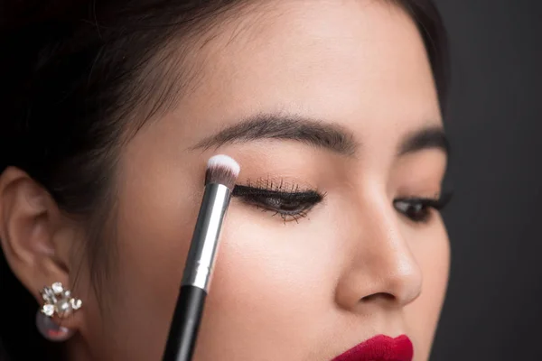 Wanita menerapkan eyeshadow pada kelopak mata . — Stok Foto