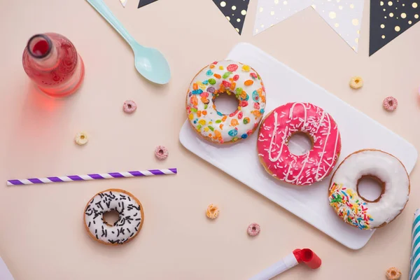 Party. Different colourful sugary round glazed donuts and bottles of drinks on light color background. — Stock Photo, Image