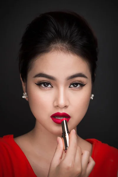 woman applying red lipstick.