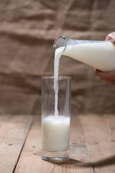 Mano vertiendo leche en el vaso —  Fotos de Stock