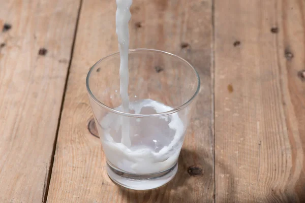 Leche vertiendo en el vaso — Foto de Stock