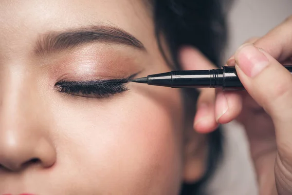 Chica tocando el delineador de ojos negro para el párpado —  Fotos de Stock