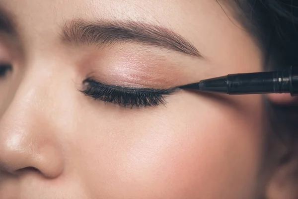 Chica tocando el delineador de ojos negro para el párpado — Foto de Stock