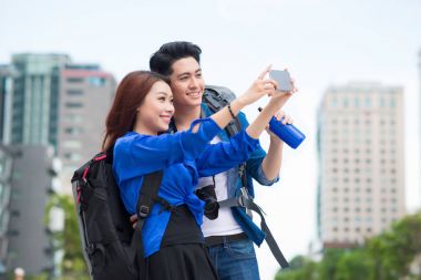 Çift akıllı telefonla selfie çekiyor.