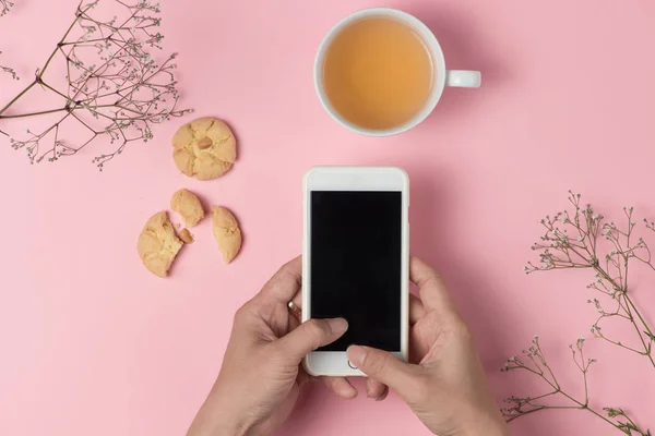 Mani con smartphone, tè e biscotti — Foto Stock