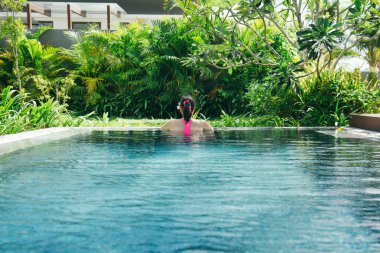 Genç kadın enjoyng güneşli bir günde lüks Havuzu. Rahatlatıcı, tropikal