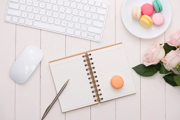 Bureau blanc avec macarons colorés, clavier et carnet ouvert . — Photo